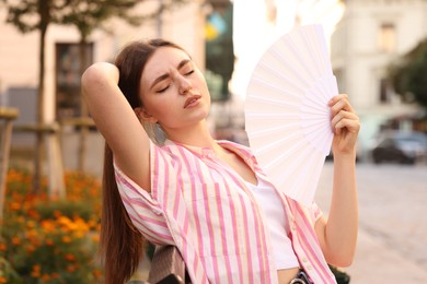 Photo of Woman with hand fan suffering from heat outdoors