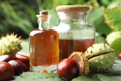 Photo of Chestnuts and essential oil on table against blurred background