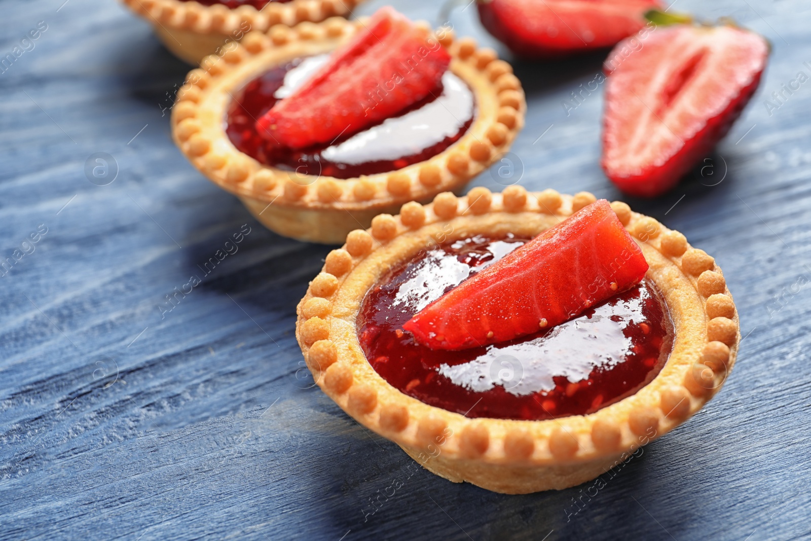 Photo of Tasty tartlets with strawberry jam on wooden background