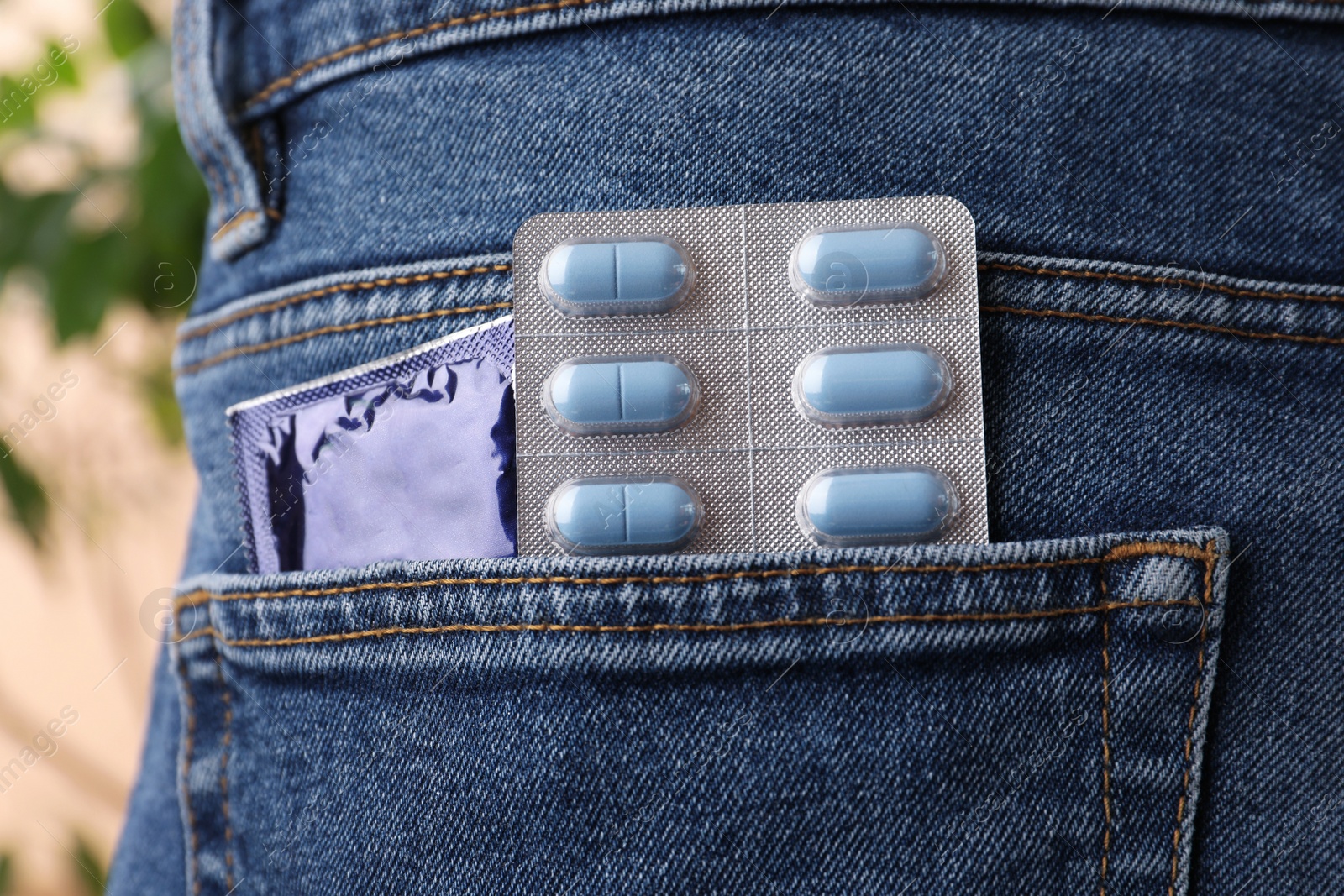 Photo of Jeans with pills and condom in pocket, closeup. Potency problem