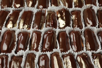 Many delicious eclairs with chocolate icing as background