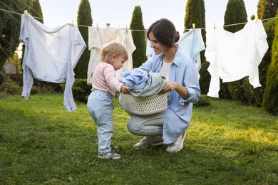Photo of Mother and daughter near washing line with drying clothes in backyard