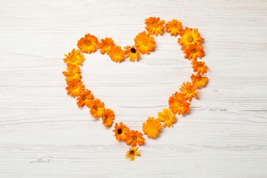 Photo of Heart of beautiful calendula flowers on white wooden table, top view