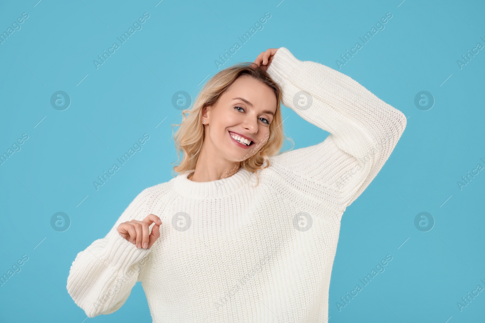 Photo of Happy woman in stylish warm sweater on light blue background