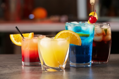 Photo of Different delicious cocktails on grey table in bar