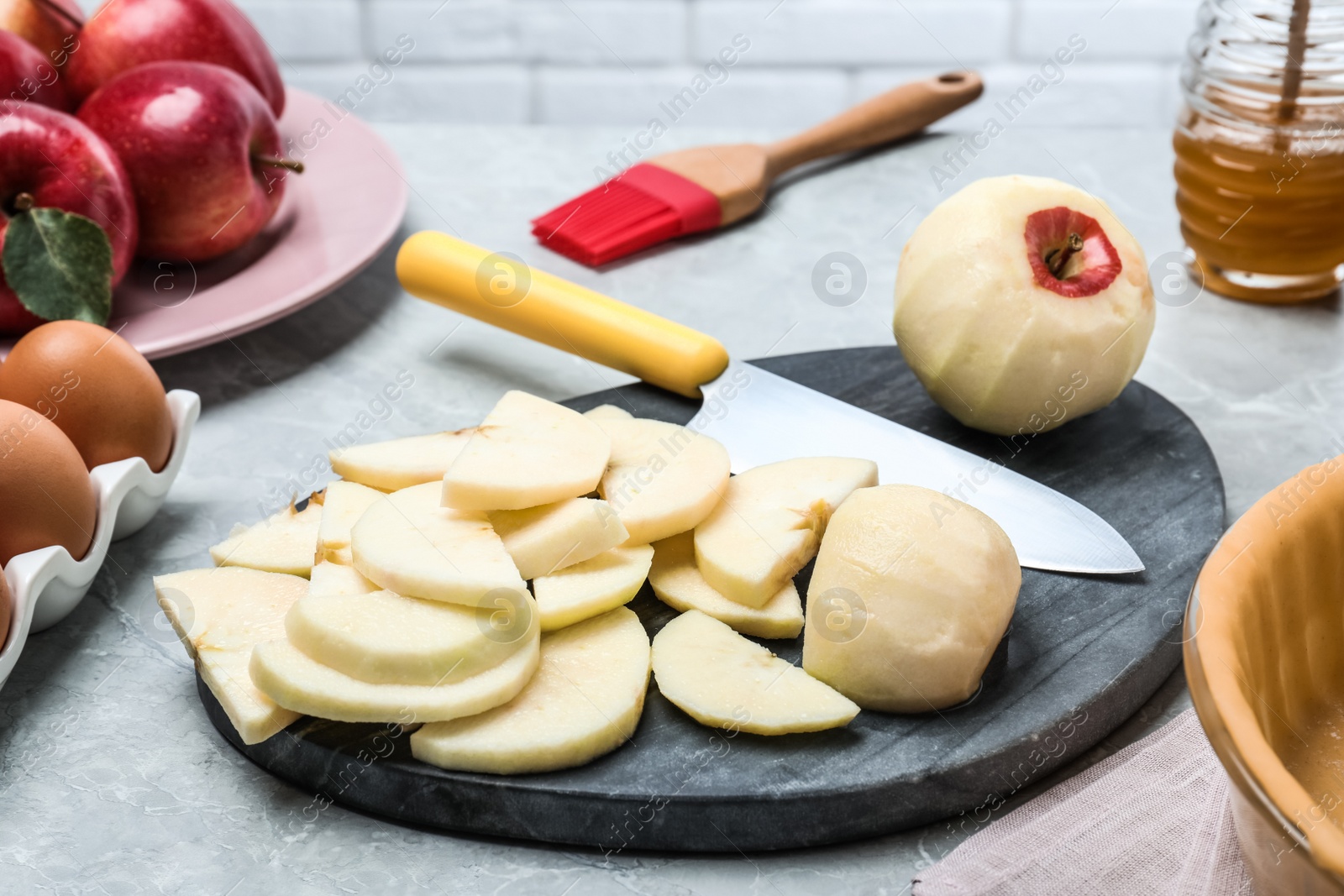 Photo of Cut fresh apple with knife and board on grey table. Baking pie