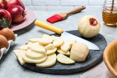 Photo of Cut fresh apple with knife and board on grey table. Baking pie