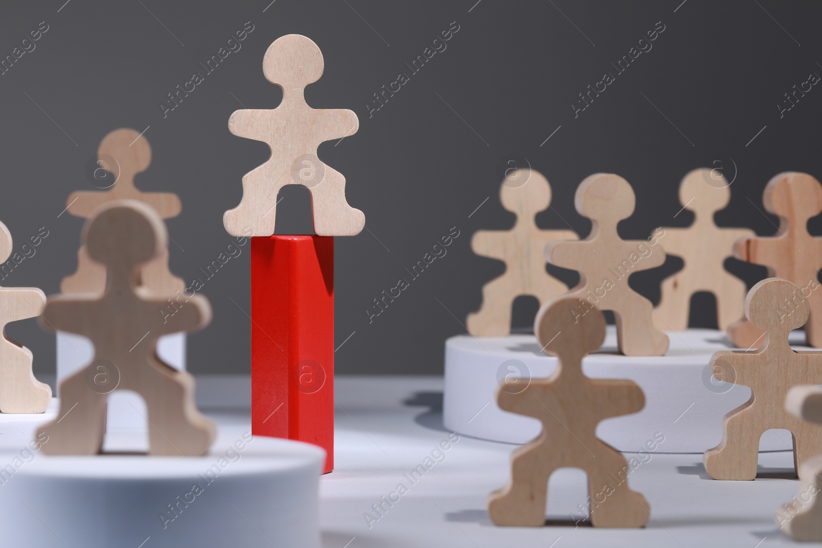 Photo of Recruitment and hiring concept. Human wooden figure on red stand among others on white table