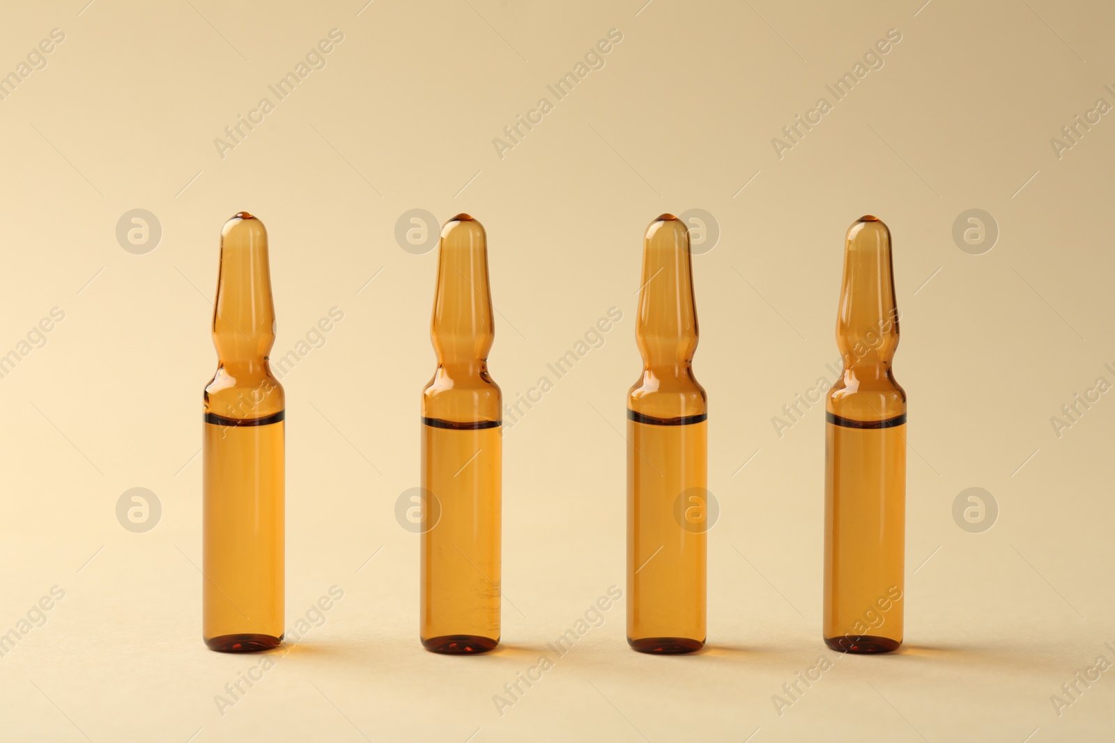 Photo of Glass ampoules with liquid on beige background