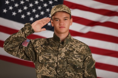 Photo of Male soldier saluting against American flag. Military service