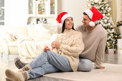 Happy couple in Santa hats at home. Christmas celebration