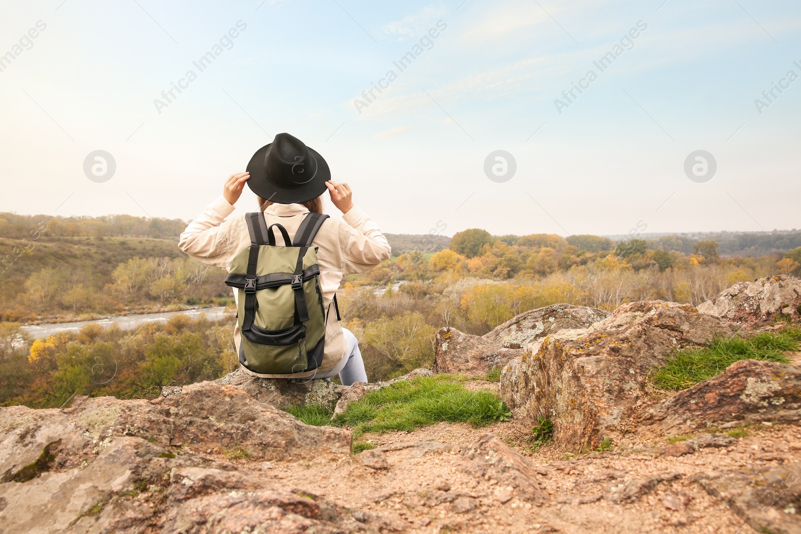 Photo of Traveler with backpack enjoying beautiful view near mountain river. Autumn vacation