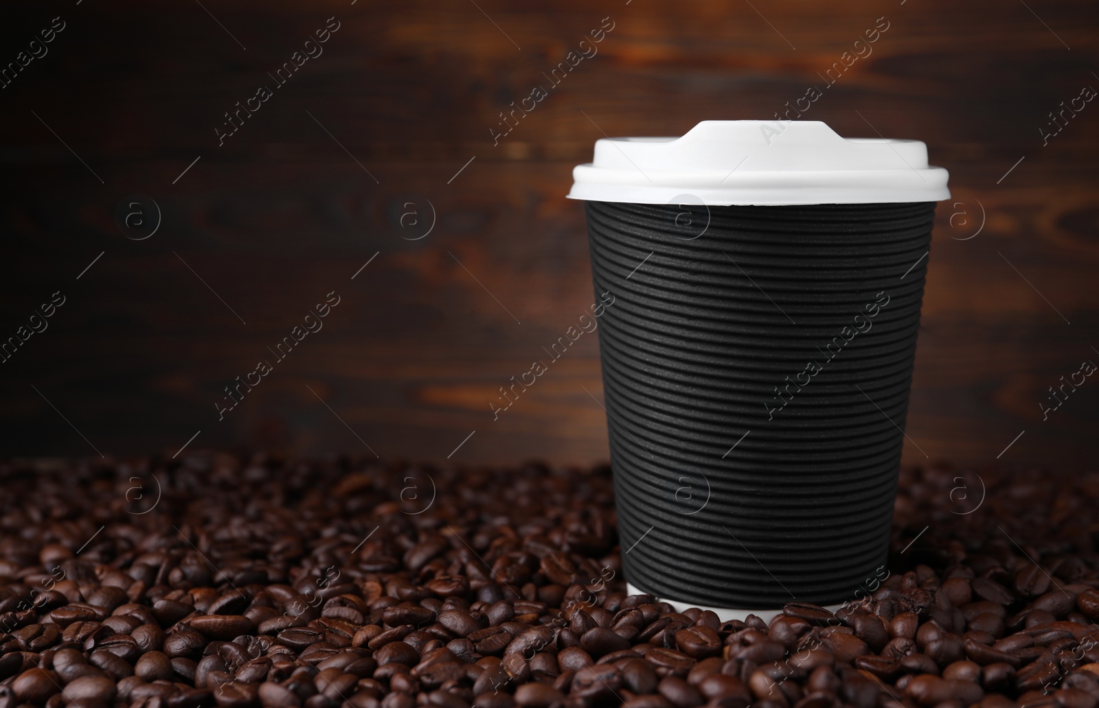 Photo of Coffee to go. Paper cup and roasted beans against wooden background, space for text