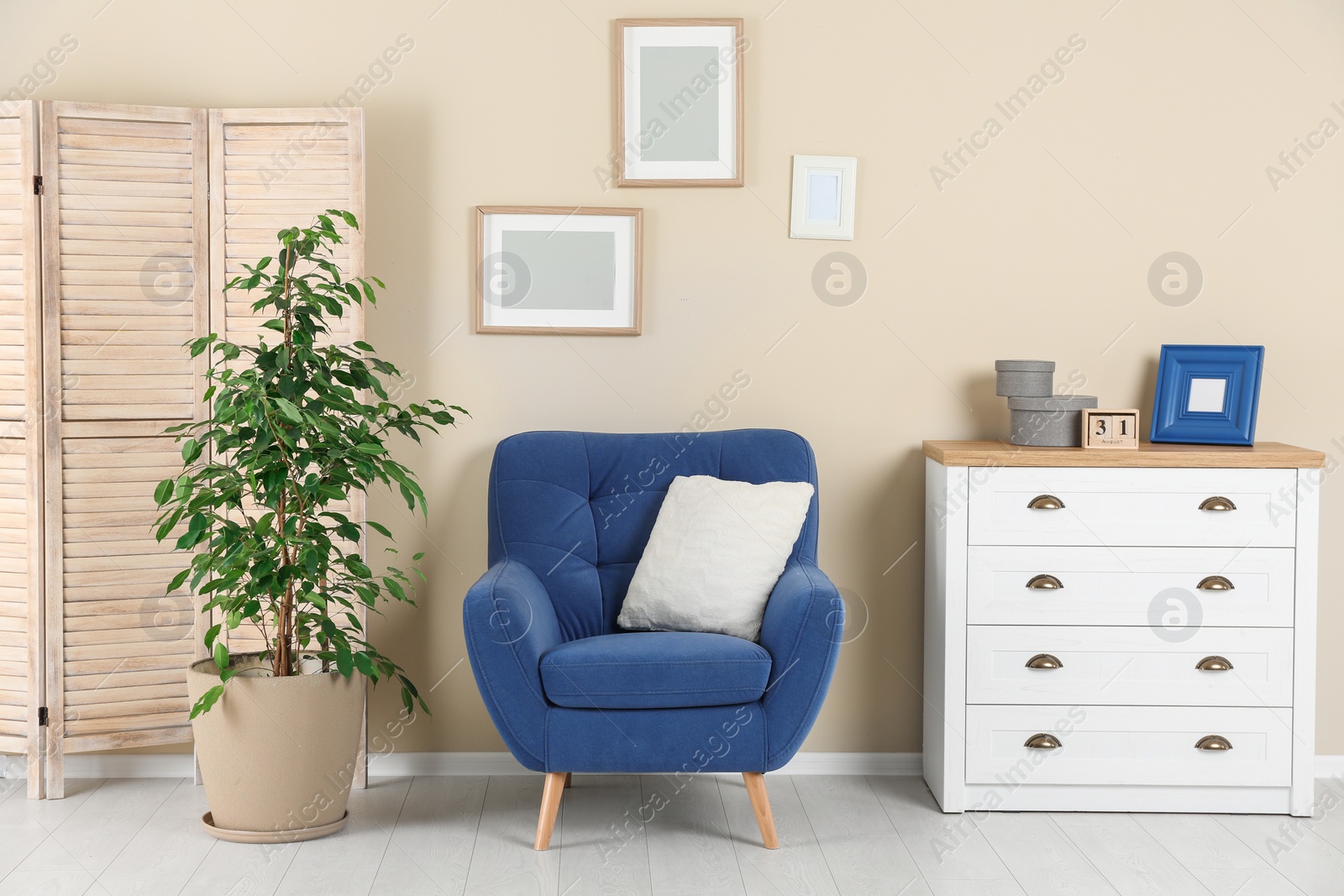 Photo of Stylish living room interior with armchair and houseplant near beige wall