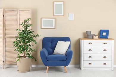 Photo of Stylish living room interior with armchair and houseplant near beige wall