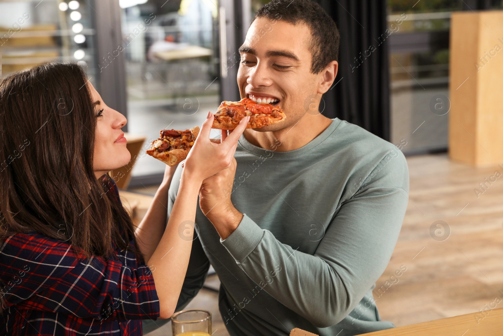 Photo of Young couple eating delicious pizza in cafe