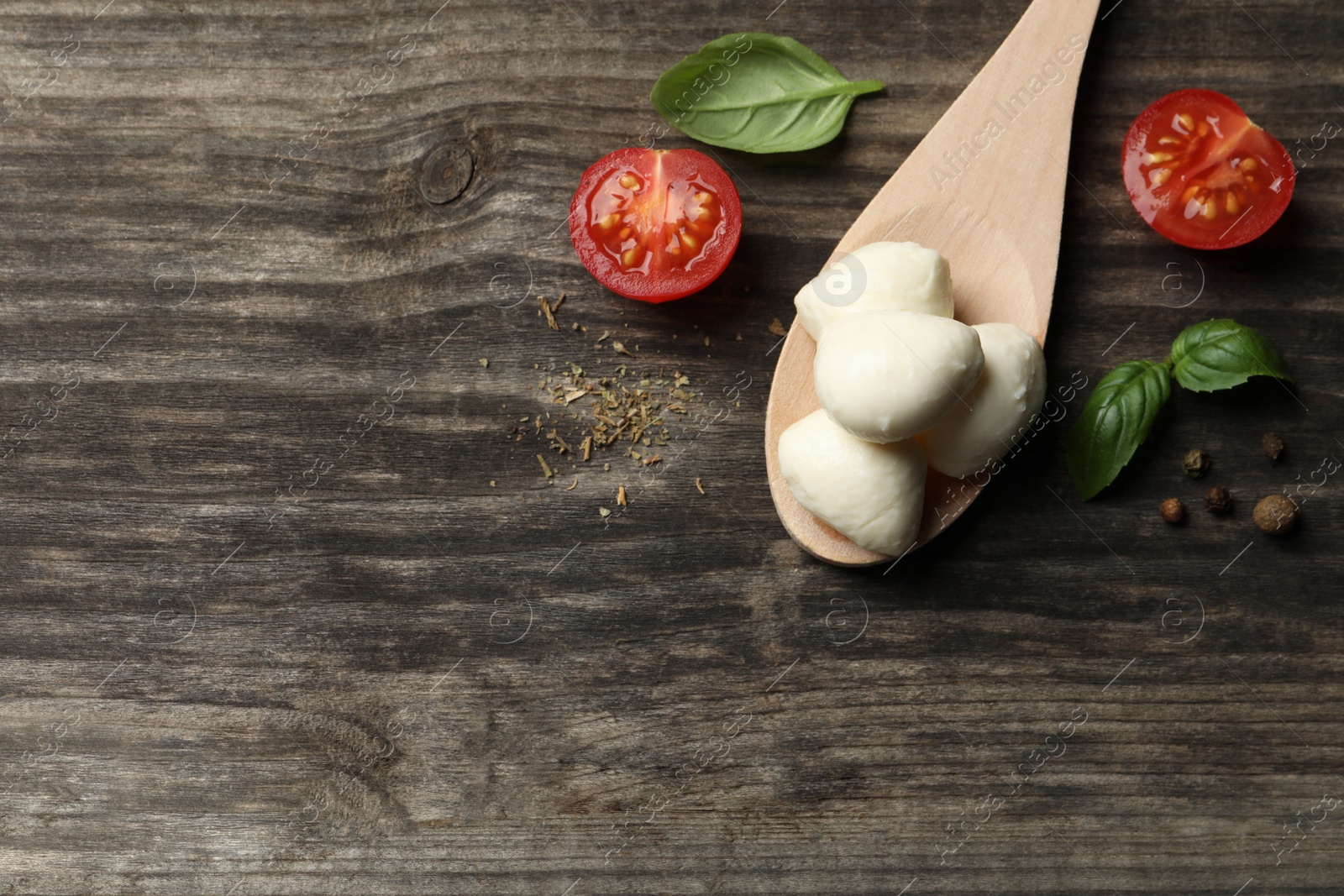 Photo of Delicious mozzarella balls, tomatoes and basil leaves on wooden table, flat lay. Space for text