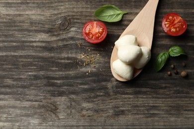 Photo of Delicious mozzarella balls, tomatoes and basil leaves on wooden table, flat lay. Space for text