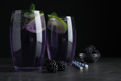 Photo of Delicious blackberry lemonade made with soda water and ingredients on grey table, closeup