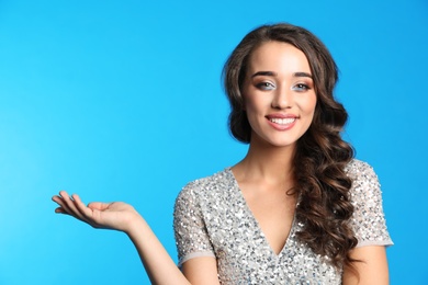 Photo of Beautiful young woman wearing elegant dress on blue background. Christmas party