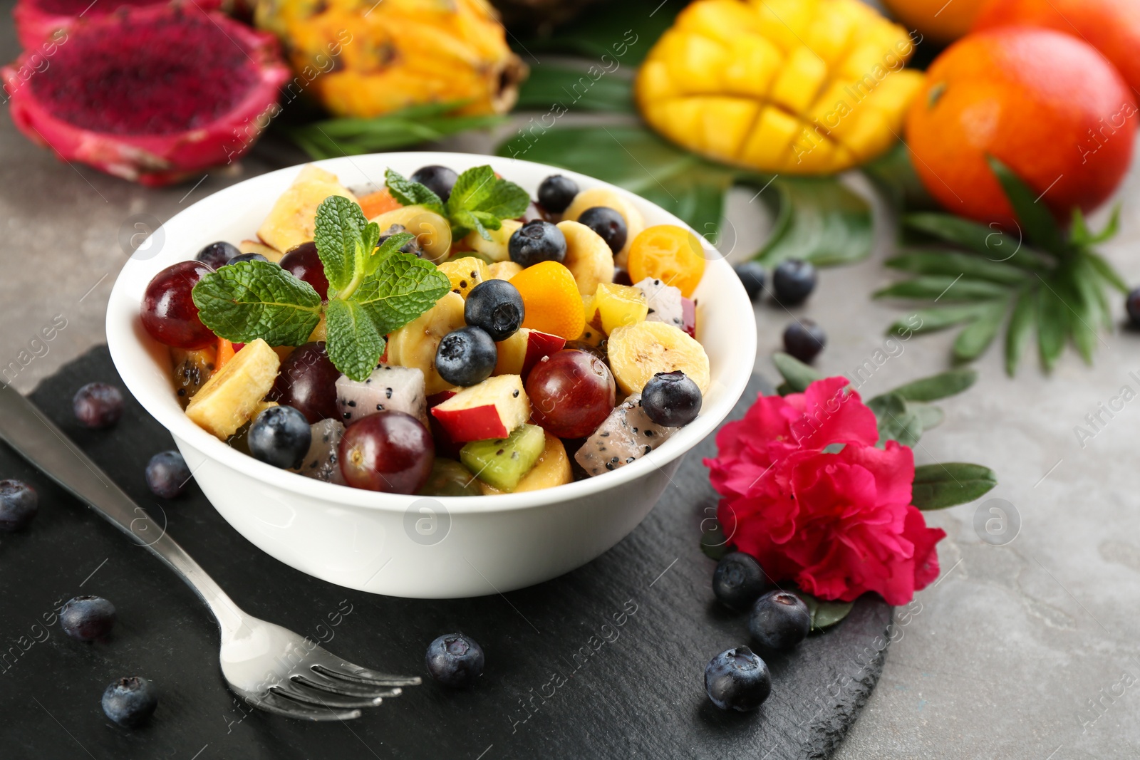 Photo of Delicious exotic fruit salad served on grey table