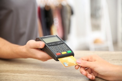 Photo of Woman using terminal for credit card payment in shop, closeup