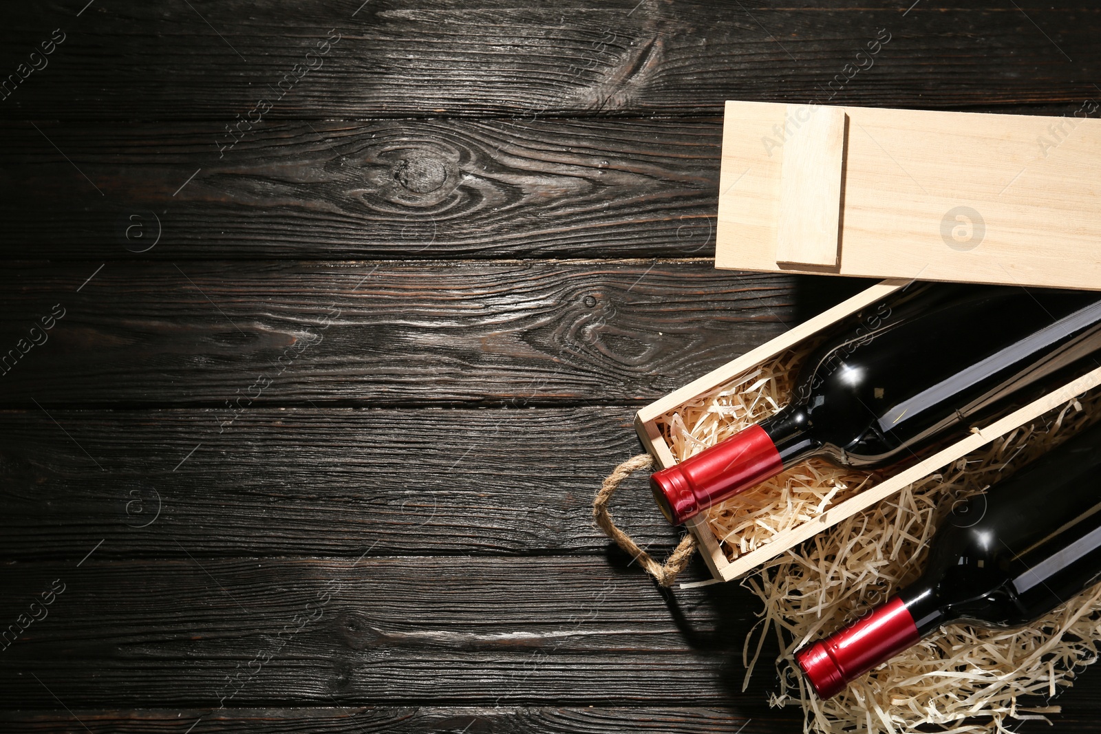 Photo of Crate and bottles of wine on wooden table, flat lay. Space for text