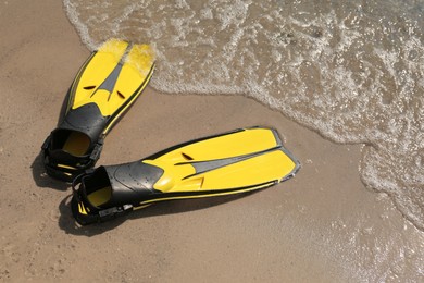 Photo of Pair of yellow flippers on sand near sea