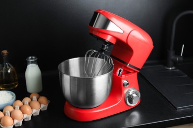 Photo of Modern stand mixer and ingredients on countertop in kitchen. Home appliance