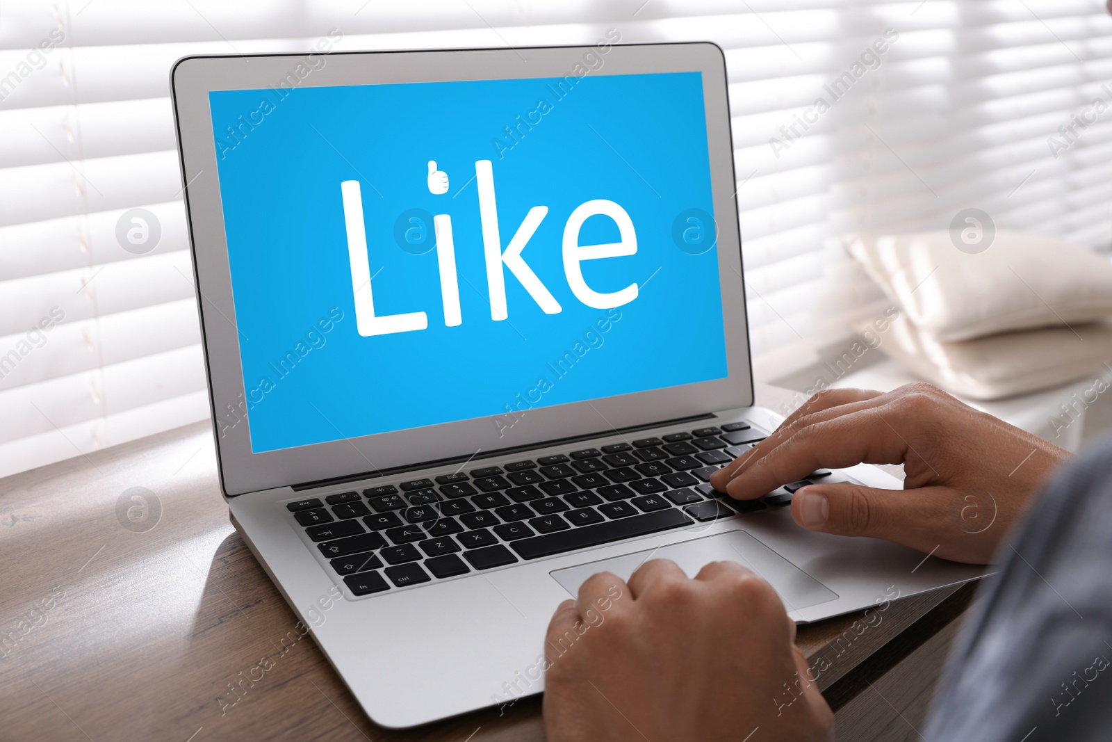 Image of Man using laptop with word Like on screen at wooden table, closeup