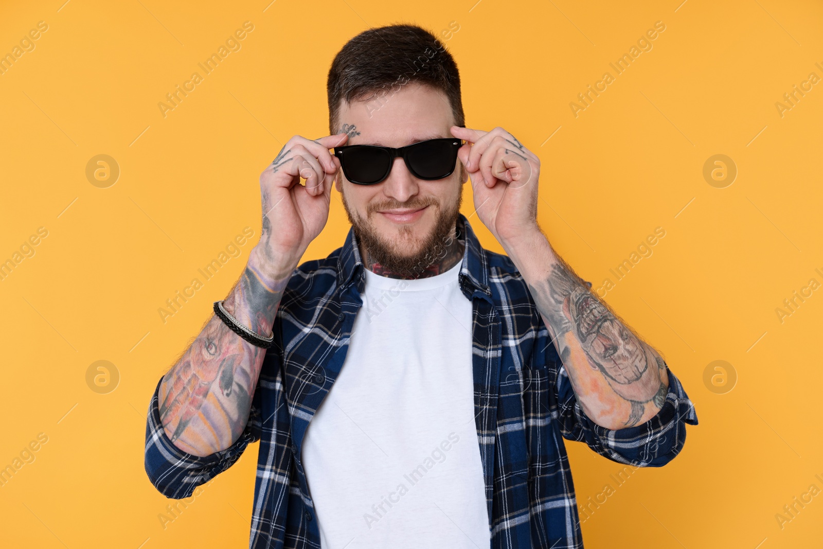 Photo of Handsome hipster man wearing stylish sunglasses on yellow background