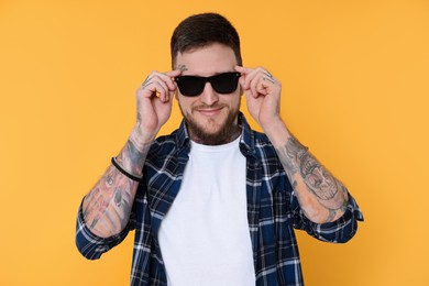 Photo of Handsome hipster man wearing stylish sunglasses on yellow background