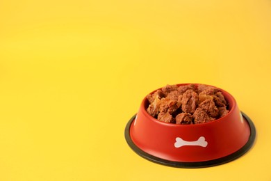 Wet pet food in feeding bowl on yellow background. Space for text