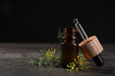 Photo of Bottle of essential oil, pipette and fresh dill on grey table, closeup. Space for text