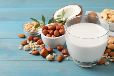 Photo of Vegan milk and different nuts on light blue wooden table. Space for text