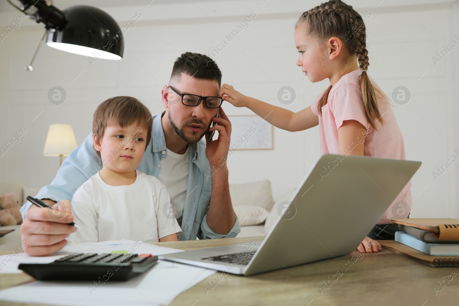 Photo of Overwhelmed man combining parenting and work at home