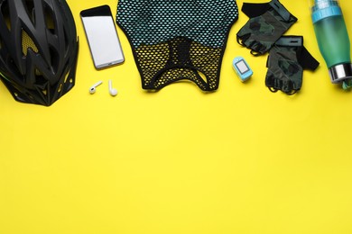 Photo of Flat lay composition with different cycling accessories and clothes on yellow background, space for text