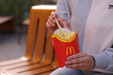 Photo of Lviv, Ukraine - September 26, 2023: Woman eating McDonald's french fries outdoors, closeup