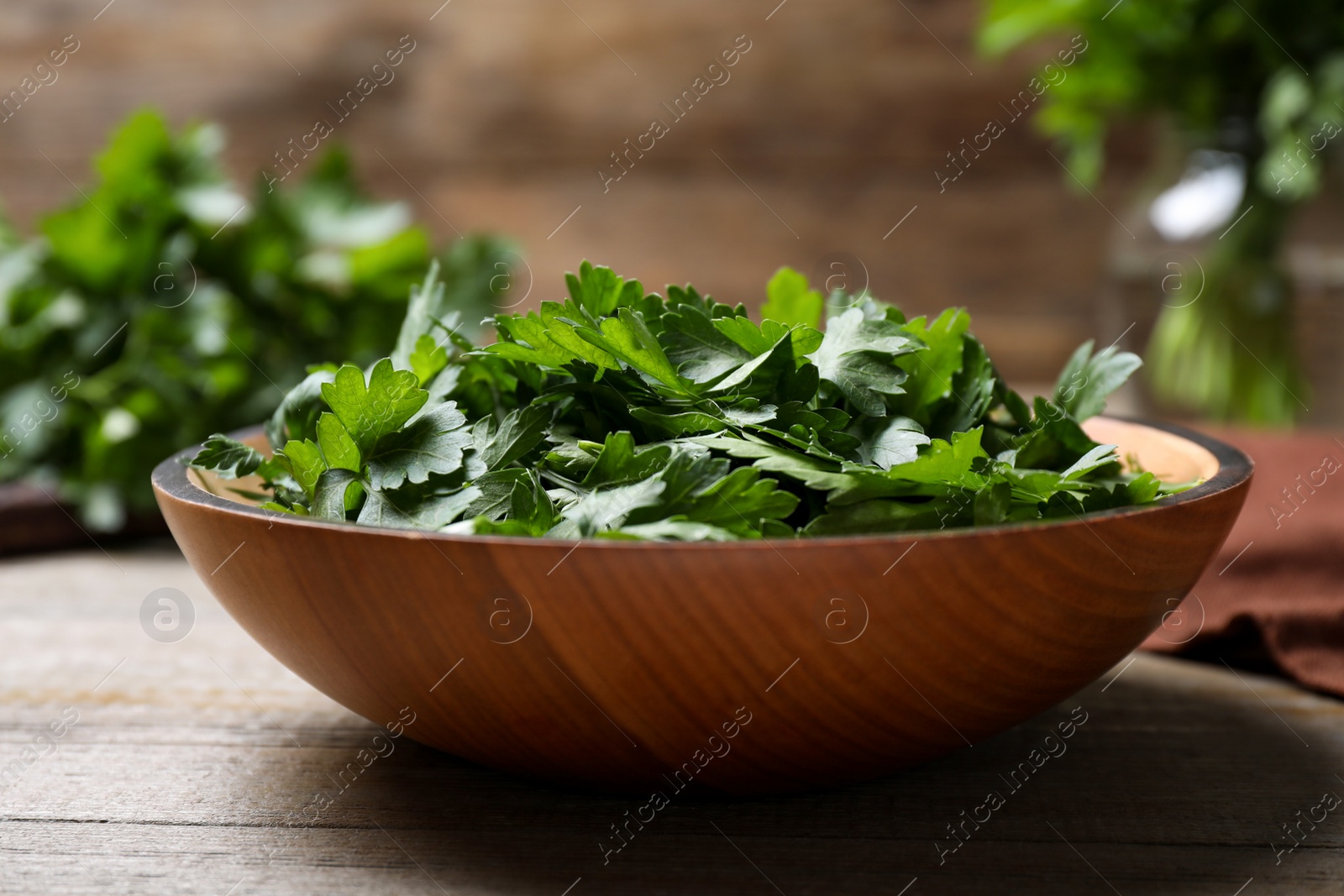 Photo of Fresh green parsley in bowl on wooden table