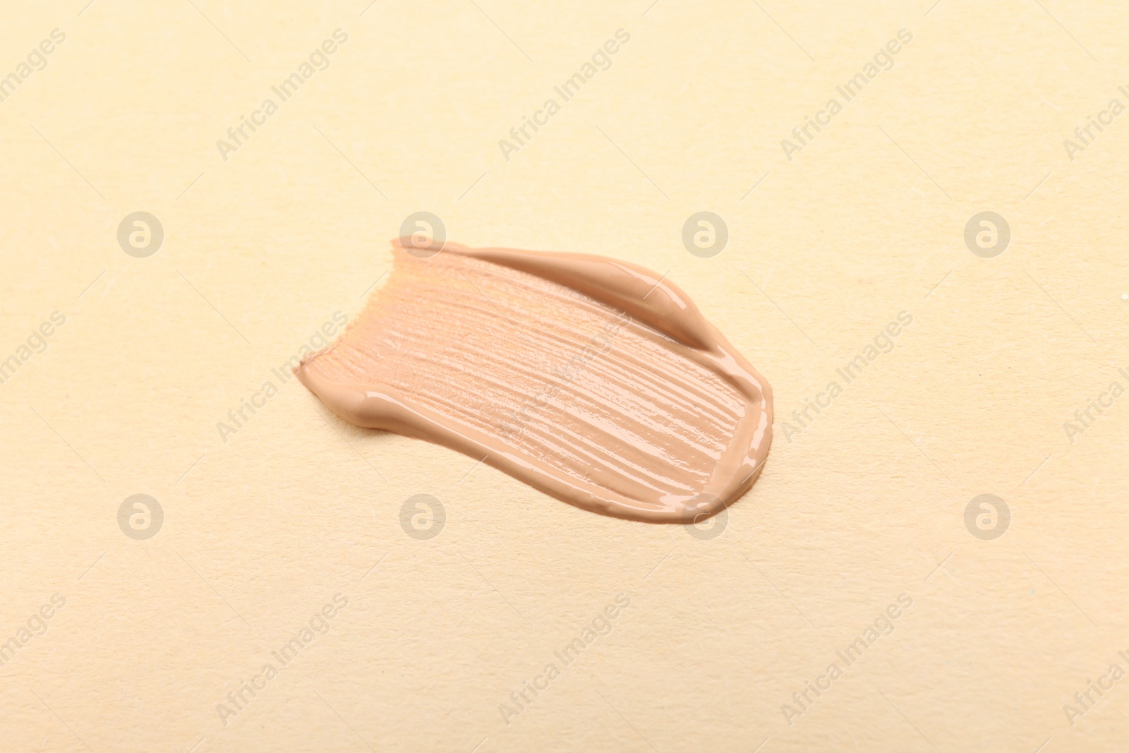 Photo of Smear of skin foundation on beige background, top view
