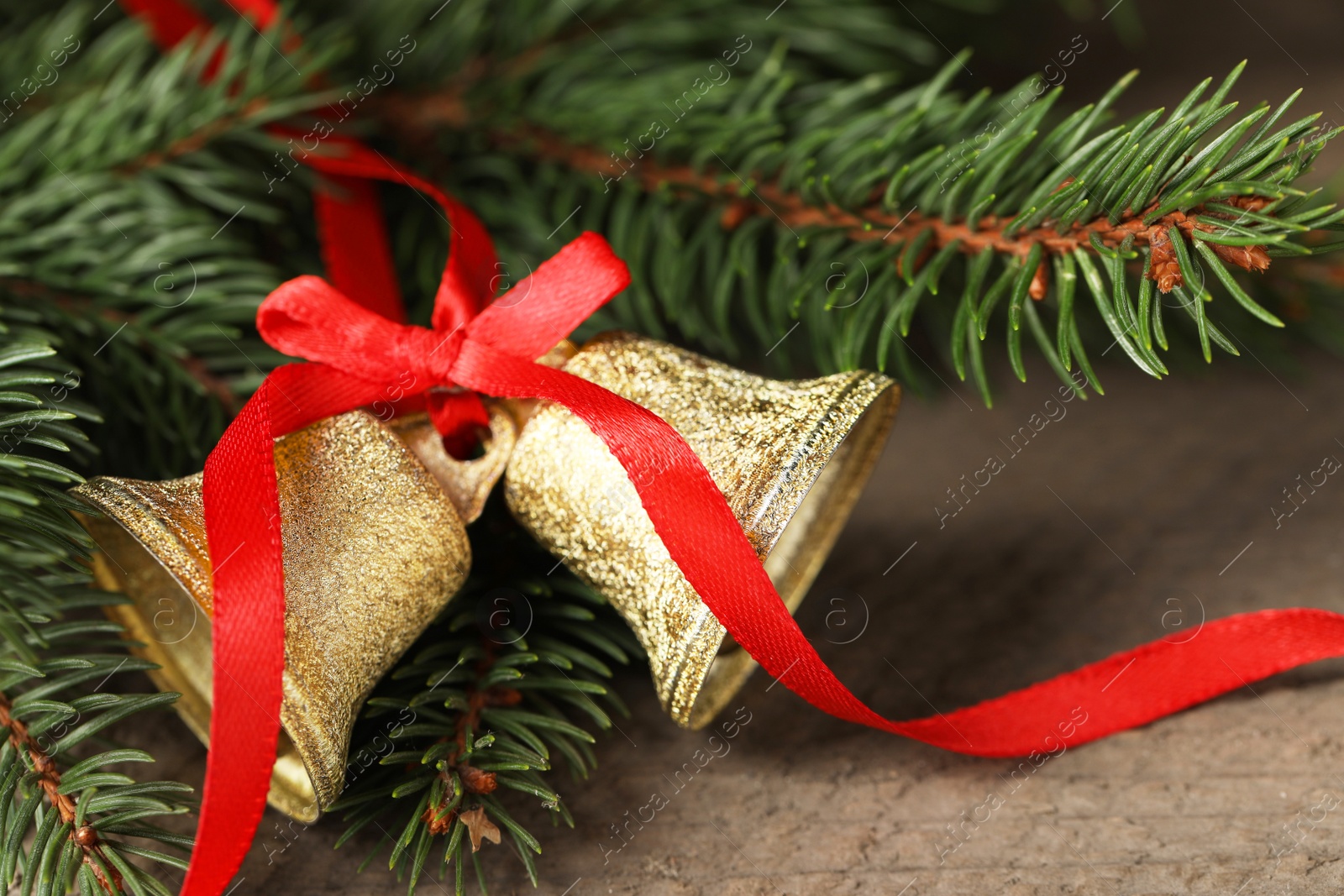 Photo of Bells and fir tree branches on wooden table, closeup. Christmas decor