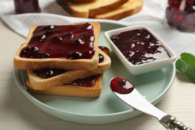 Photo of Delicious toasts with jam served on white wooden table, closeup