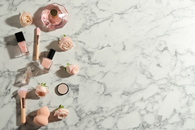 Flat lay composition with bottles of perfume, cosmetics and roses on marble background, space for text