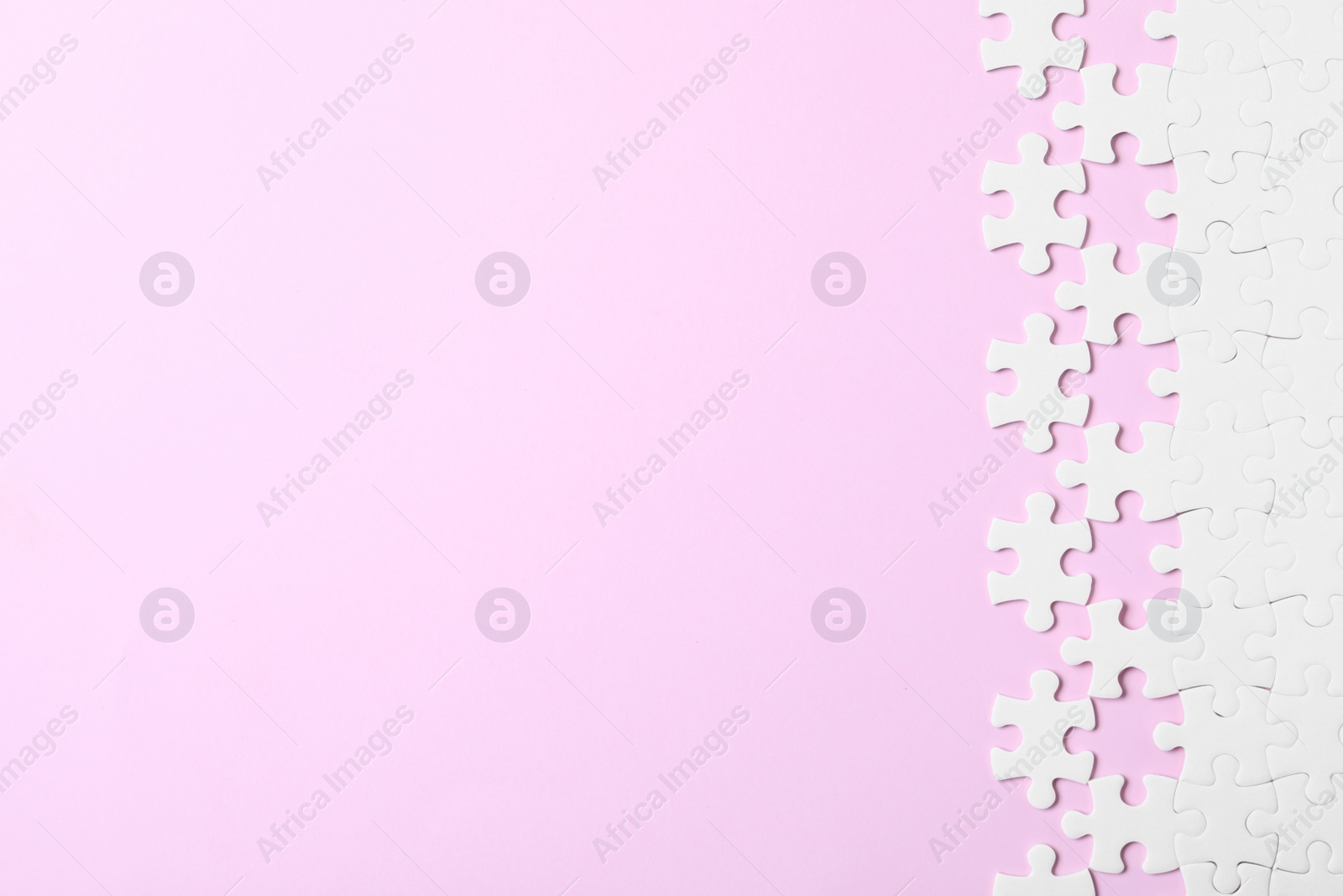 Photo of White puzzle with separated pieces on pink background, flat lay. Space for text