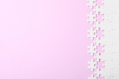 Photo of White puzzle with separated pieces on pink background, flat lay. Space for text