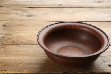 Beautiful empty clay bowl on wooden table
