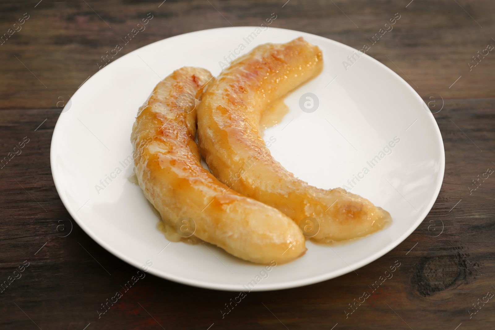 Photo of Plate with delicious fried bananas on wooden table