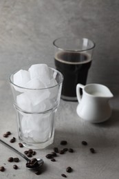 Making iced coffee. Ice cubes in glass, ingredients and spoon on gray table