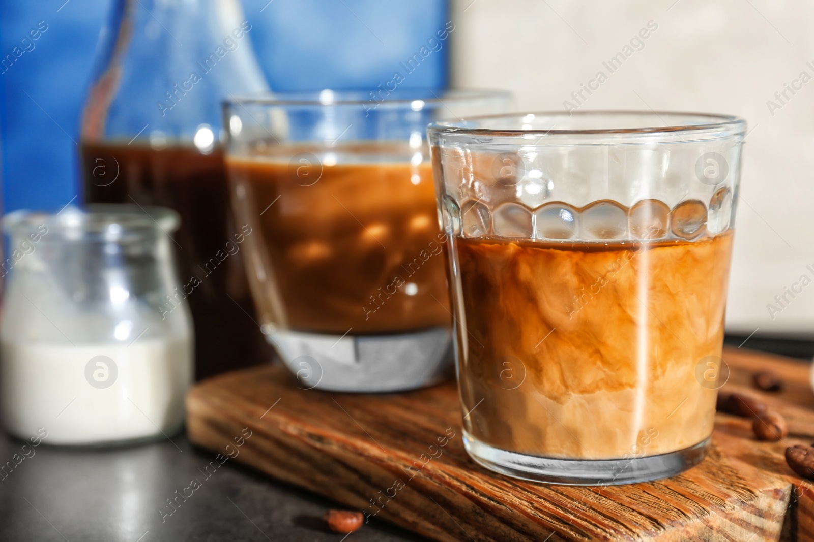 Photo of Glasses with cold brew coffee and milk on wooden board