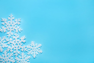 Beautiful decorative snowflakes on light blue background, flat lay. Space for text